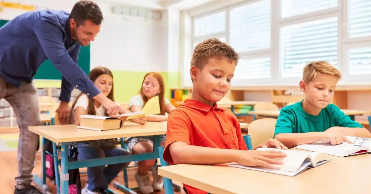 Leerkracht begeleidt leerlingen tijdens het lezen in de klas